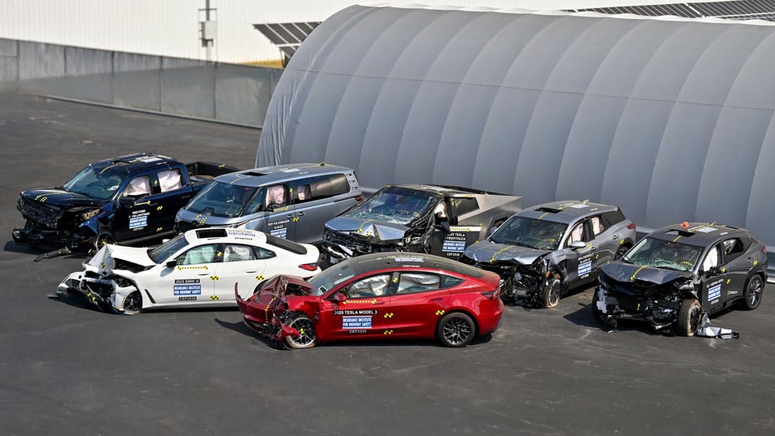 Seven post-crash electric vehicles arranged outside an IIHS test facility after moderate overlap front crash testing, including the Tesla Model 3, Ford F-150 Lightning, Chevrolet Blazer EV, Tesla Cybertruck, Volkswagen ID.Buzz, Nissan Ariya, and BMW i4