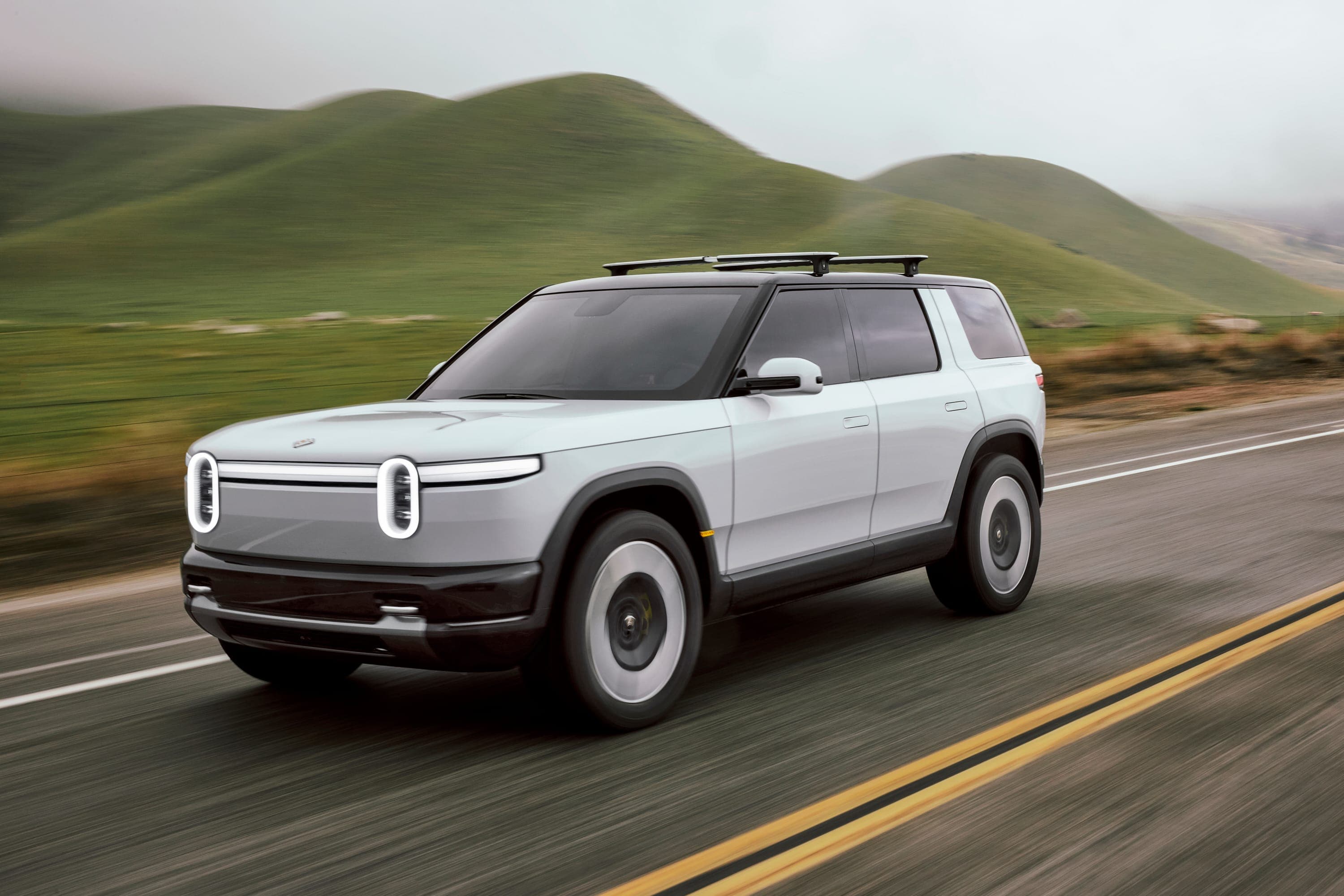 Rivian R2 electric SUV parked on an overlook with mountain landscape in the background